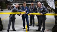 Joukko armeijapukuisia miehiä leikkaamassa puolustusvoimien uusien varastotilojen avajaisnauhaa.