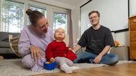 Isä ja äiti hassuttelevat lapsensa kanssa olohuoneen lattialla.