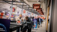 Customers packing groceries at a supermarket checkout.