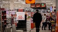 En gång i en matbutik med några människor som handlar. Många skyltar med erbjudanden syns.