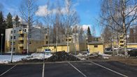 Piha-alueella näkyy parkkipaikka, keväistä sulavaa lunta ja taustalla kerrostaloja.