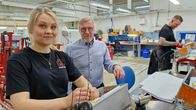 Hymyilevät nainen ja mies sähköalan yrityksen asennuslinjalla.