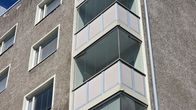 Koulukadun varrella oleva kerrostalo, jossa on useita lasitettuja parvekkeita.