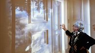 Nainen seisomassa ovea esittävän valokuvataideteoksen edessä.