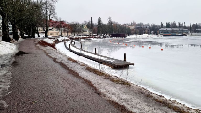 Talvinen näkymä Saimaan rannalta Lappeenrannasta, missä kävelytie kulkee lumen peittämän rannan vieressä jäätyneen veden äärellä.