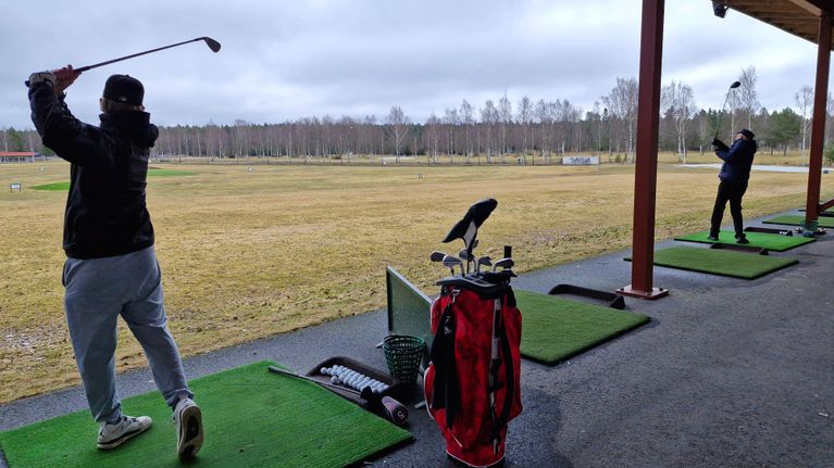 Kaksi miesgolfaria lyömässä harjoituslyöntejä Vaasassa.