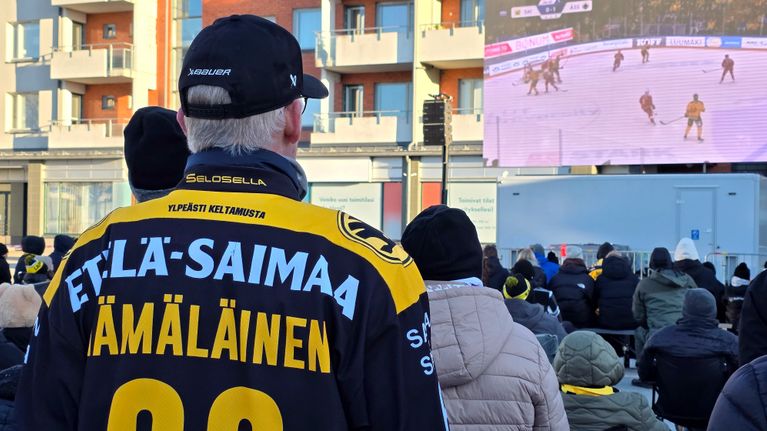 SaiPan faneja Lappeenrannan kauppatorilla katsomassa SaiPa-Ässät peliä isolta screeniltä.
