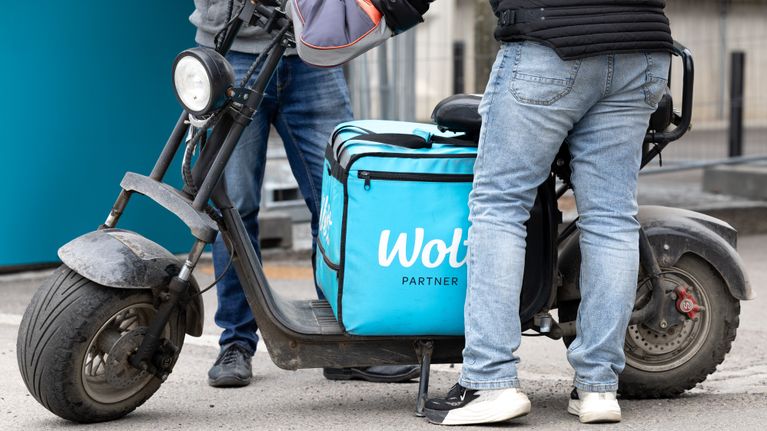 Wolt-kuski antaa ruokalähetyksen miehelle. 