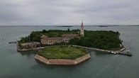Ilmakuvassa Poveglia saaresta. Saaressa lehtipuista ja kaksi rakennusta.