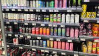 A collection of different branded energy drinks in a shop fridge. Price tags are seen on the shelves.