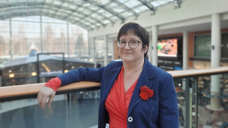 Näyttelypäällikkö Kirsi Mutka-Paintola nojailee kaiteeseen aurinkoisessa Kauppakeskus Stellassa. 