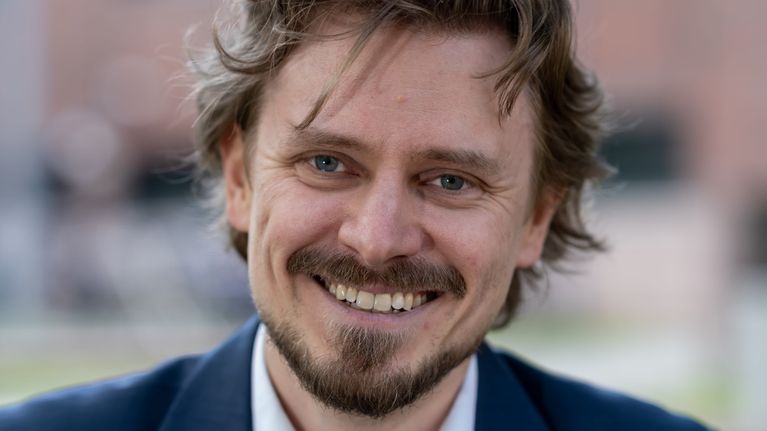 Mies istumassa ulkona pöydän ääressä.