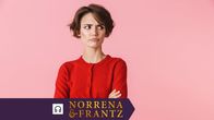 Ung bister kvinna i röda kläder står framför en rosa bakgrund med korslagda armar.