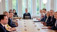 Presidentti Alexander Stubb istuu puisen pöydän ääressä ministereiden kanssa.
