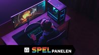En person sitter i ett mörkt rum och spelar datorspel med hörlurar på.