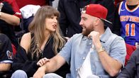 Taylor Swift och Travis Kelce ler och pratar med varandra medan de följer med en basketmatch i Ohio. 