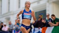 Juoksija kilpailuasussa juoksee kadulla yleisön edessä, paidassa teksti "VAINIO".