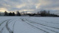 Däckspår på en snötäckt gräsplan.