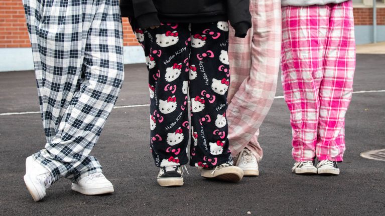 Yläasteikäisiä tyttöjä seisomassa rivissä koulun pihalla. Kaikilla on jalassaan pyjamahousut.