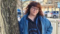 Alexandra Furubacka står lutad mot ett träd och ser in i kameran.