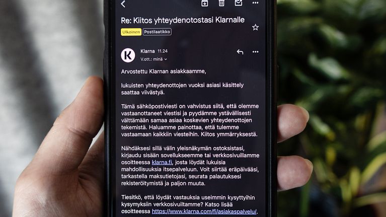 Käsi pitelee puhelinta, jossa näkyy Klarnan sähköpostivastaus.