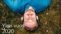 Mies makaa maassa silmät kiinni ja kuullokkeet päässään. Kuvan päällä teksti Ylen vuosi 2019.