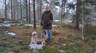 Daniela Andersson står en skog med lite snö på marken. Hon har sin hund Orvar i koppel.