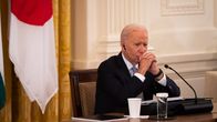 Joe Biden sitter vid ett bord med händerna framför ansiktet och en orolig min.