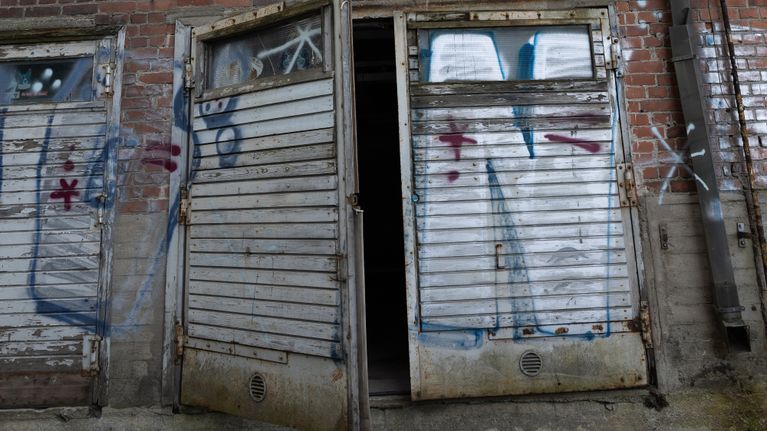 Hylätyn rakennuksen rikotut ikkunat ja graffitit kertovat paikan pitkään jatkuneesta käyttämättömyydestä.