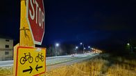 Stop-merkki tien reunassa. Edessä maantie, jossa valaistus vaihtuu sinertävistä ledeistä vanhaan kellertävään sävyyn.