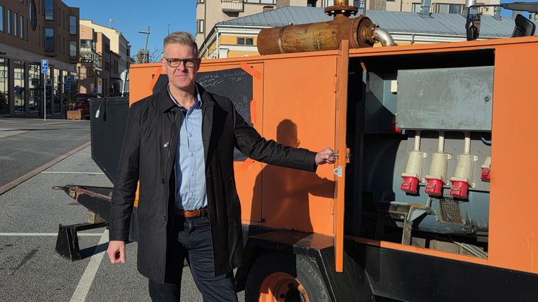 En man som står vid en generator på ett torg. 