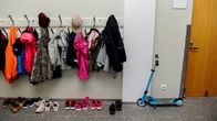 Kuvassa on koululaisten vaatteita naulakossa.