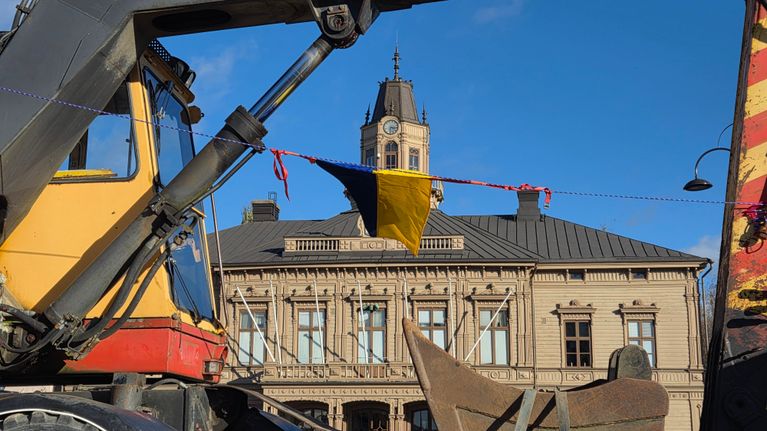 En grävmaskin som står på ett torg. 