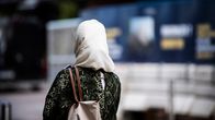 Woman walking on the street seen from behind wearing a white hijab headscarf.