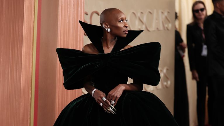 Cynthia Erivo leveä helmaisessa tumman vihreässä sametti mekossa punaisella matolla.
