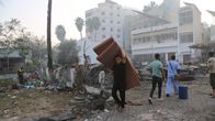 Mies kantaa patjoja Gaza Cityssä keskiviikkona 18.10., lähellä ohjusosuman saanutta al-Ahlin sairaala.