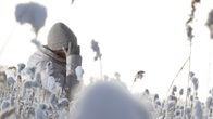 Valkotakkinen nainen lumisella pellolla.