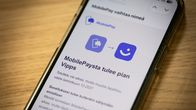 En smarttelefon på ett träbord. På skärmen syns ett pressmeddelande av Mobilepay där bolagets nya namn och logo syns.
