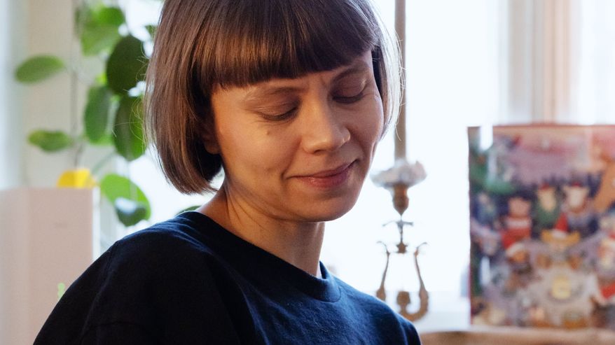Nainen pitelee kissaa sylissään ja katsoo sitä lempeästi.