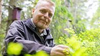 Janne Sivonen pitelee kädellään mustikanvarpua. Taustalla metsää.