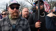 Alex Jones mielenosoituksessa kahden aurinkolasipäisen miehen välissä.