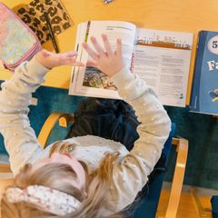 Photo shows a child sitting at a school desk.