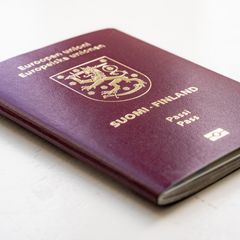 Lähikuva Suomen passista vaalealla taustalla.