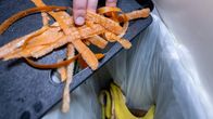 Henkilö laittaa porkkanankuoria biojäteastiaan.