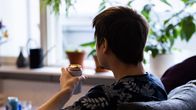 En man som sitter i en soffa och dricker öl.