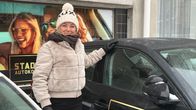 Pipopäinen nainen pitää toista kättään henkilöauton katolla.