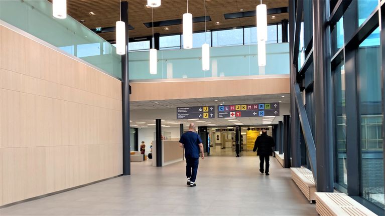 Hoitaja ja asikas kävelevät Päijät-Hämeen keskussairaalan käytävällä. 