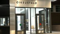 Kuvassa on vierekkäin monta lasista sisääkäyntiovea, jotka ovat kiinni. Ovien yläpuolella lukee Oikeustalo.