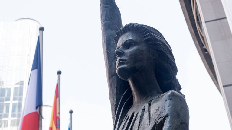 Euroopan parlamentin edessä oleva patsas, joka pitää euron symbolia kädessä.