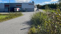 Kuoma-yrityksen tehdas, etualalla vihreää pusikkoa.